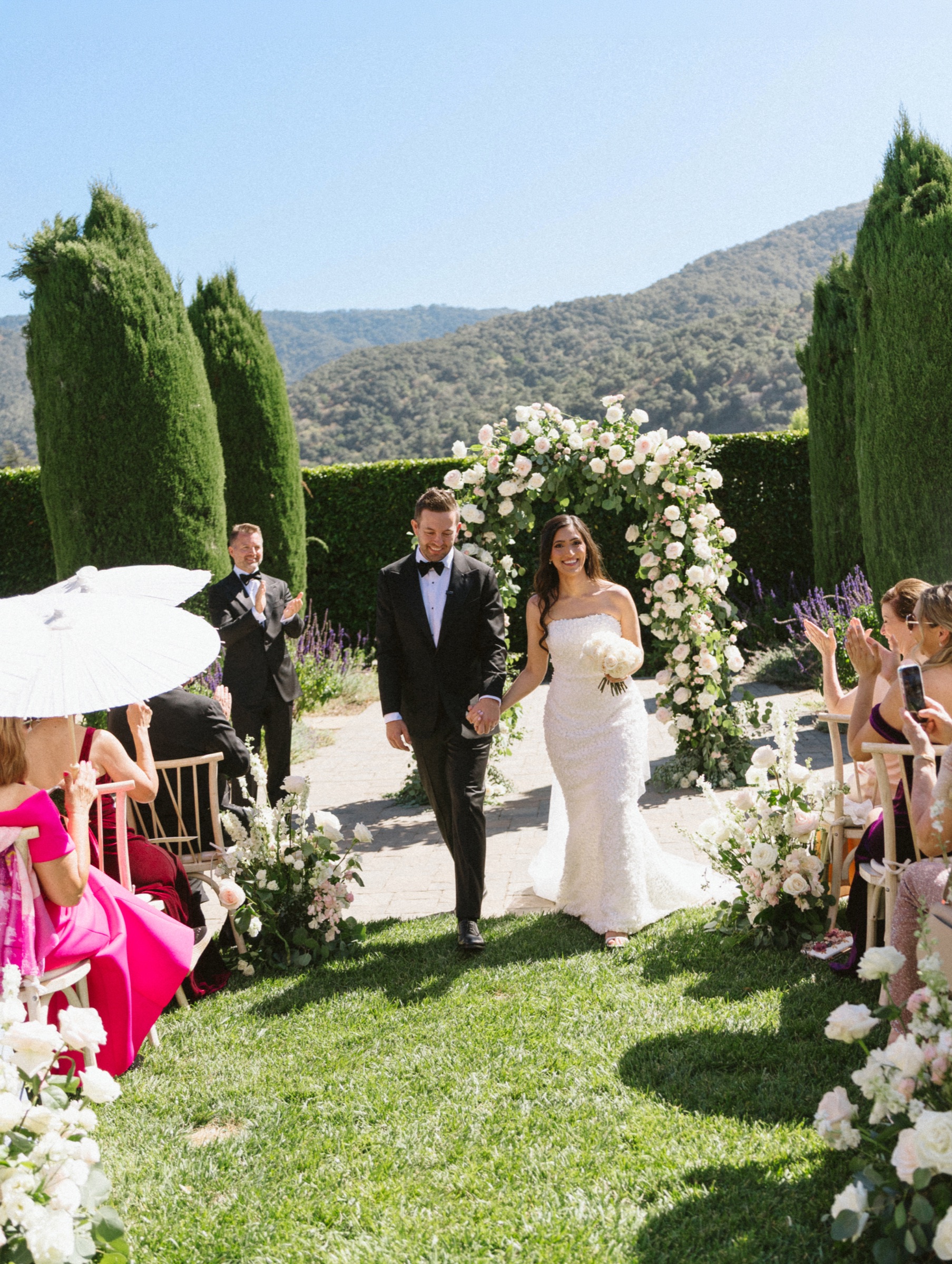 Newlyweds walking hand in hand from their outdoor wedding ceremony